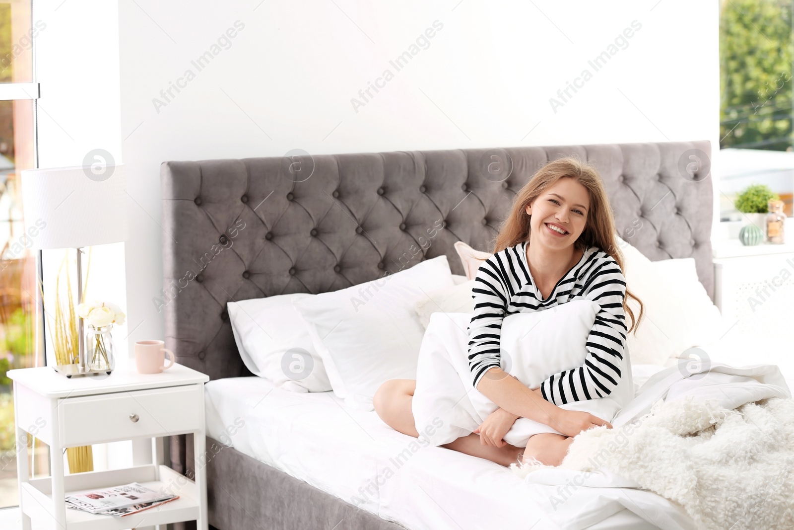Photo of Young woman embracing pillow on bed at home. Peaceful morning
