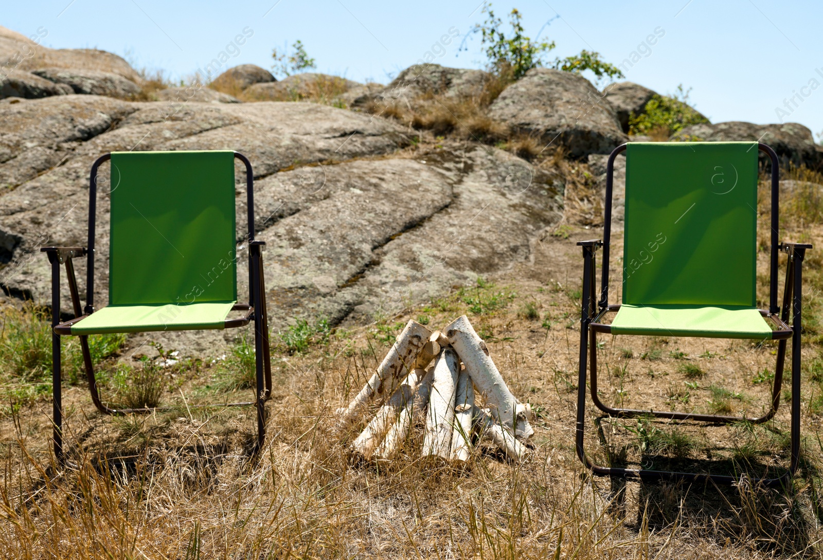 Photo of Chairs and dry firewood arranged for bonfire outdoors