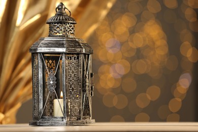 Photo of Arabic lantern on table against blurred lights, space for text