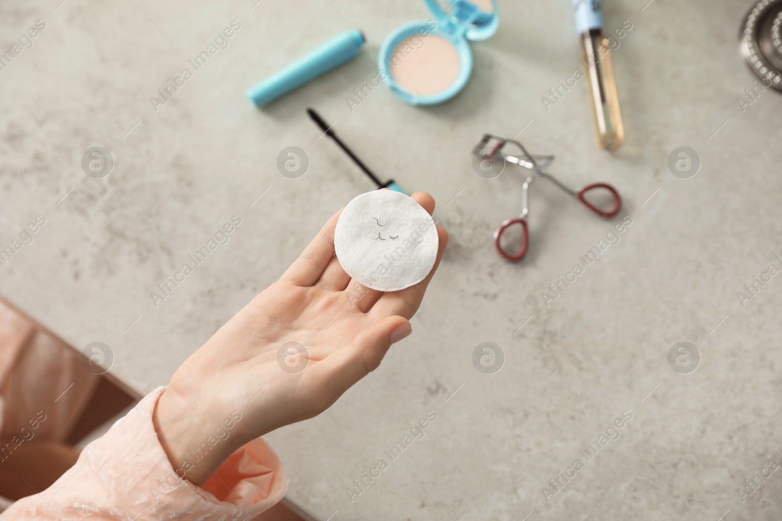 Photo of Young woman holding cotton pad with fallen eyelashes over table