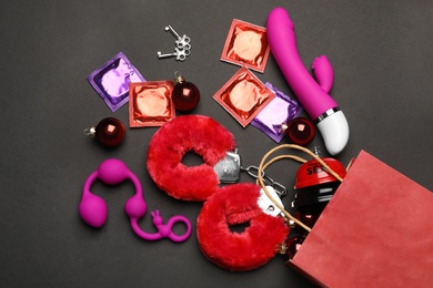 Photo of Shopping bag and different sex toys on black background, flat lay