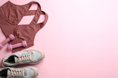 Photo of Sportswear and dumbbells on pink background, flat lay with space for text. Gym workout