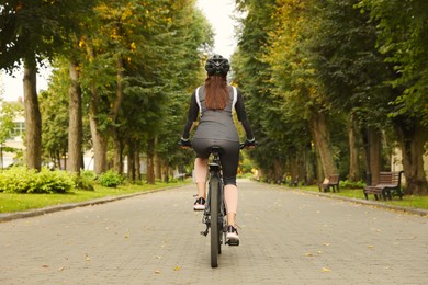 Photo of Woman riding bicycle on road outdoors, back view