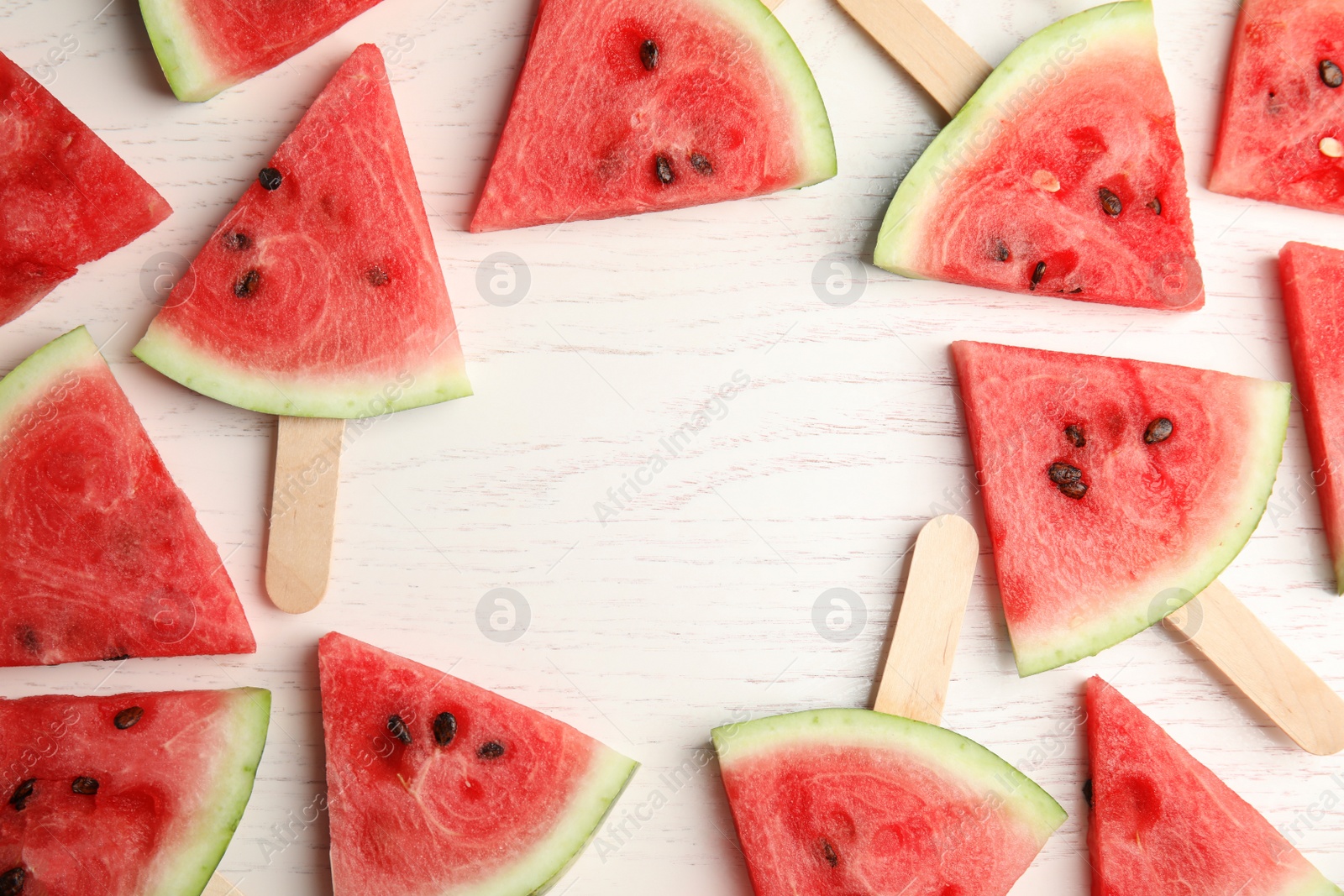 Photo of Frame made with slices of ripe watermelon on white wooden table background, flat lay. Space for text
