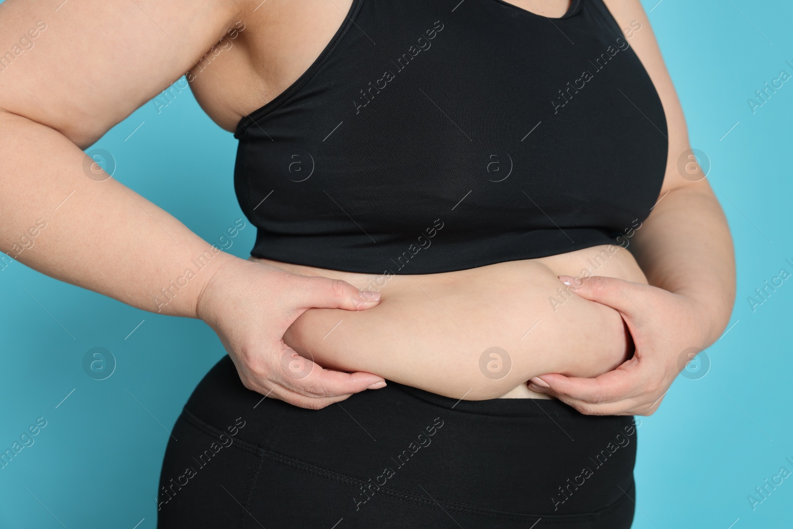 Photo of Obese woman on light blue background, closeup. Weight loss surgery