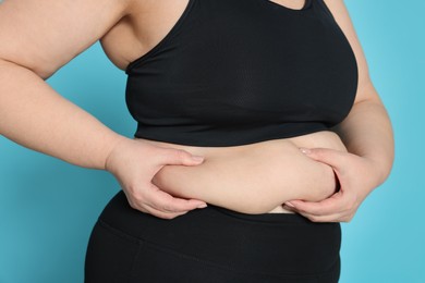 Obese woman on light blue background, closeup. Weight loss surgery