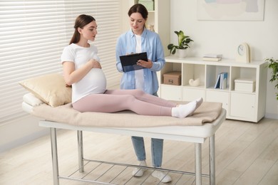 Doula working with pregnant woman indoors. Preparation for child birth