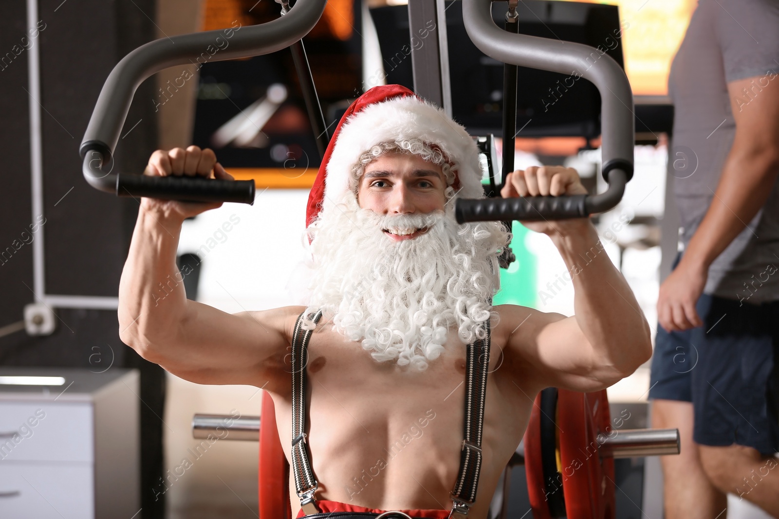 Photo of Young muscular man in Santa costume training at gym