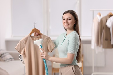 Woman steaming shirt on hanger at home