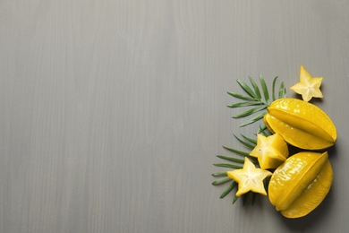 Delicious carambola fruits on grey wooden table, flat lay. Space for text