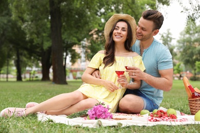 Happy young couple having picnic in park on summer day