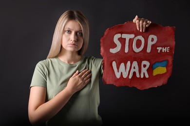 Sad woman holding poster with words Stop the War on black background