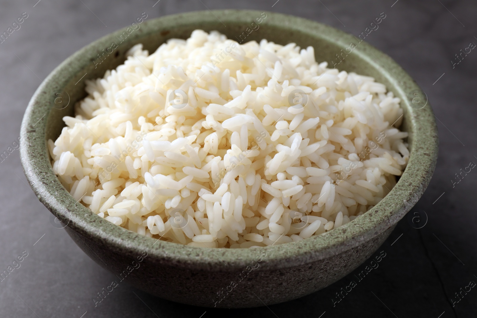 Photo of Delicious rice in bowl on grey table, closeup