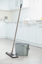 Photo of Mop and plastic bucket in kitchen. Cleaning supplies