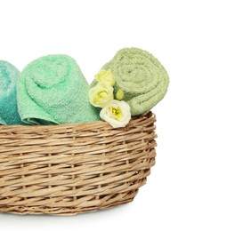 Photo of Wicker basket with rolled soft terry towels and flowers on white background