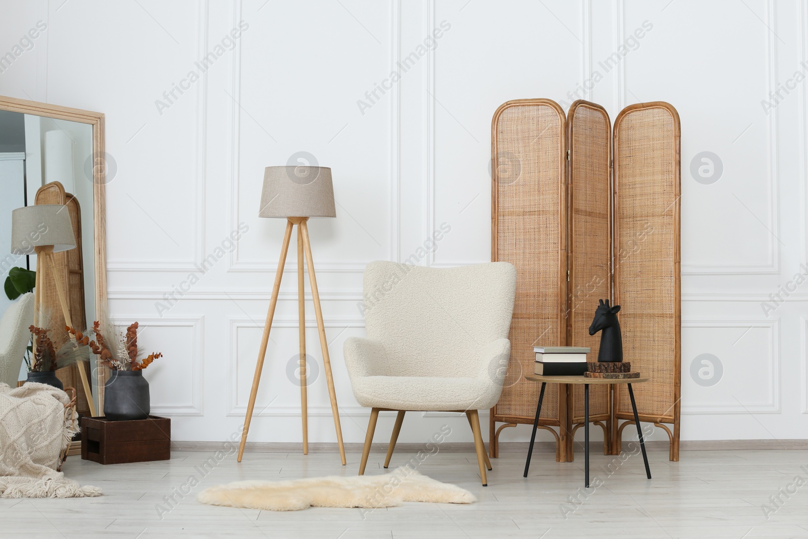 Photo of Stylish beige armchair, small coffee table and mirror in living room. Interior design