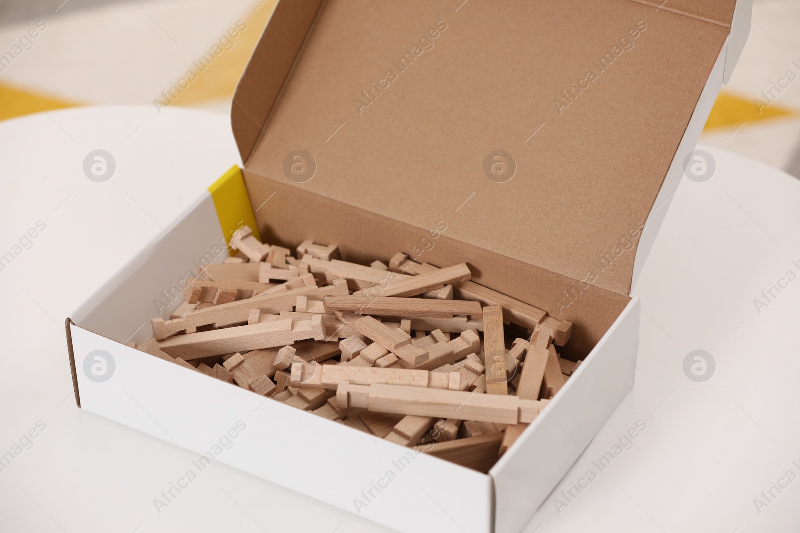 Photo of Box with wooden building blocks on white table, closeup. Educational toy for motor skills development