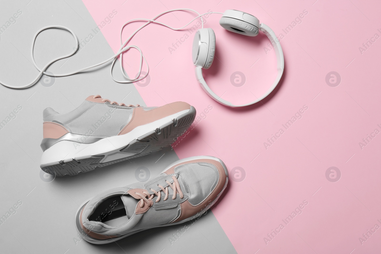 Photo of Flat lay composition with pair of sport shoes and headphones on color background. Space for text