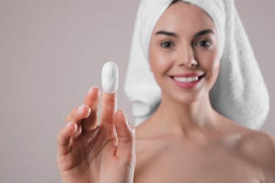 Photo of Woman with silkworm cocoon against light grey background, focus on hand. Skin care routine