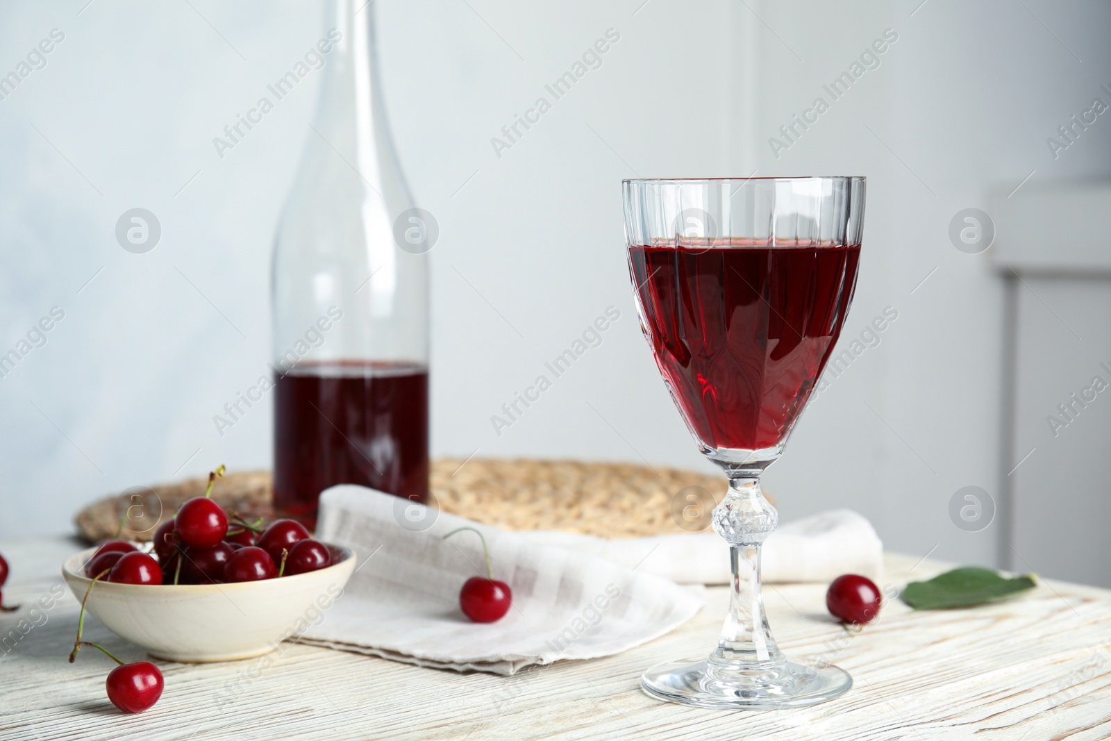 Photo of Delicious cherry wine with ripe juicy berries on white wooden table indoors