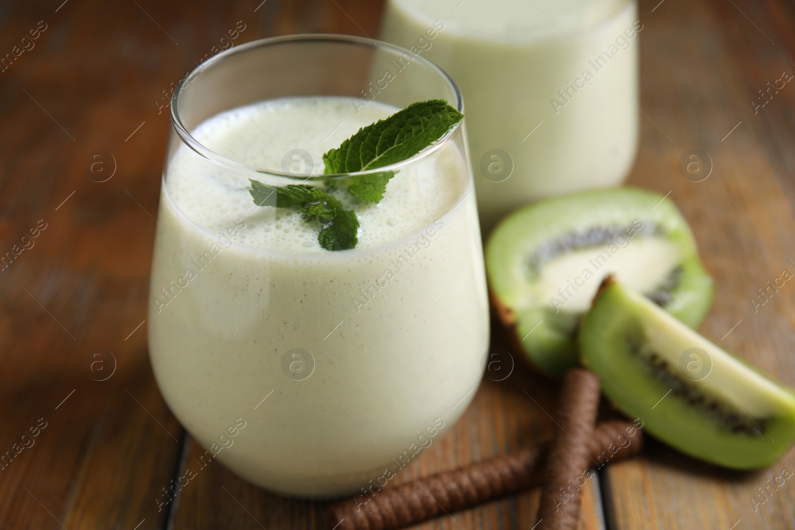 Photo of Tasty milk shake with kiwi on wooden table, closeup