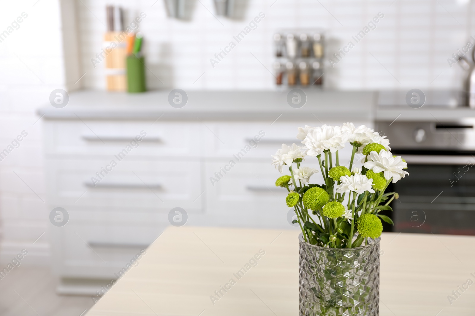 Photo of Vase with beautiful flowers on table in kitchen interior. Space for text