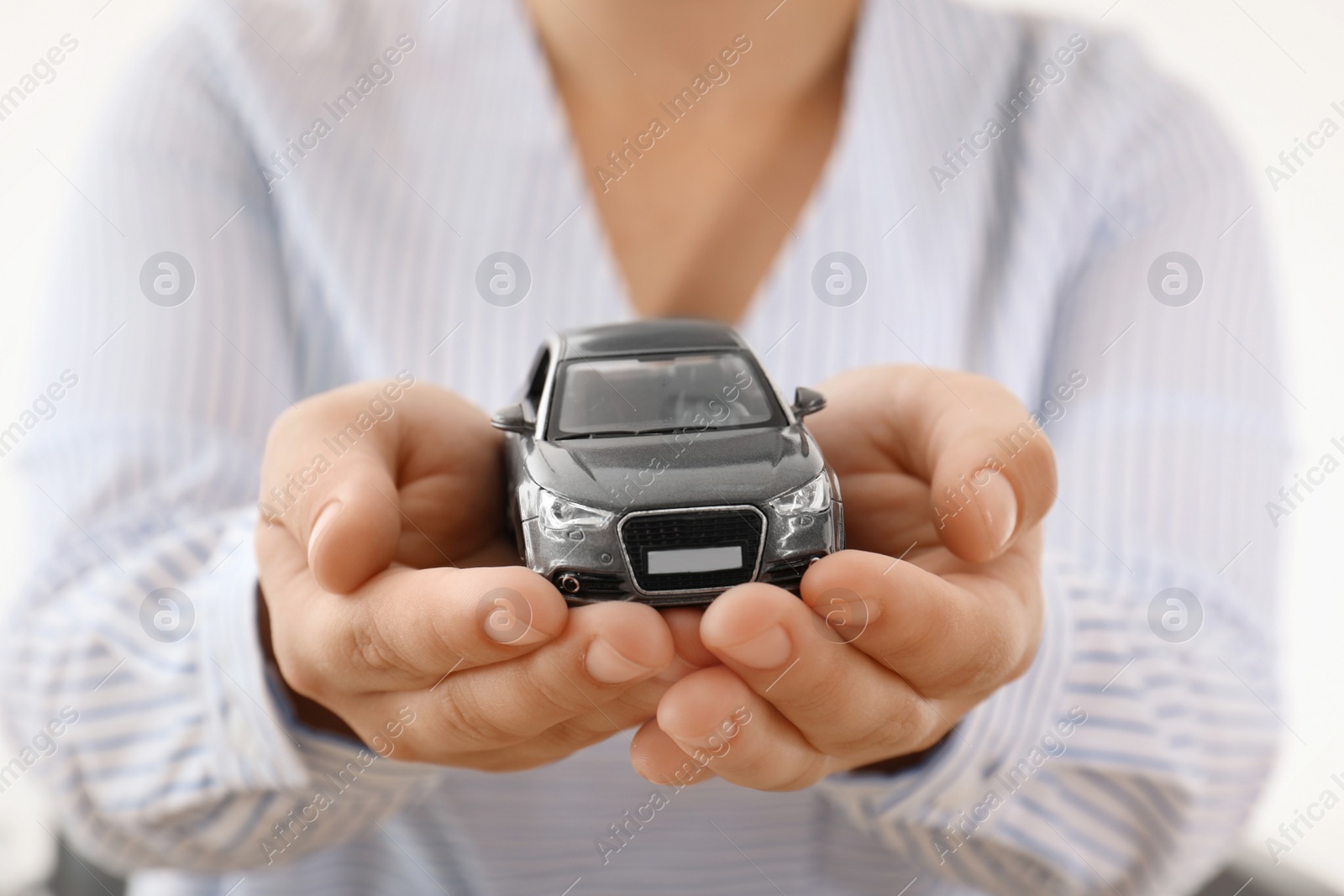 Photo of Female insurance agent holding toy car, closeup