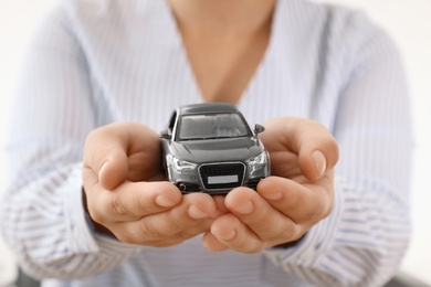 Photo of Female insurance agent holding toy car, closeup