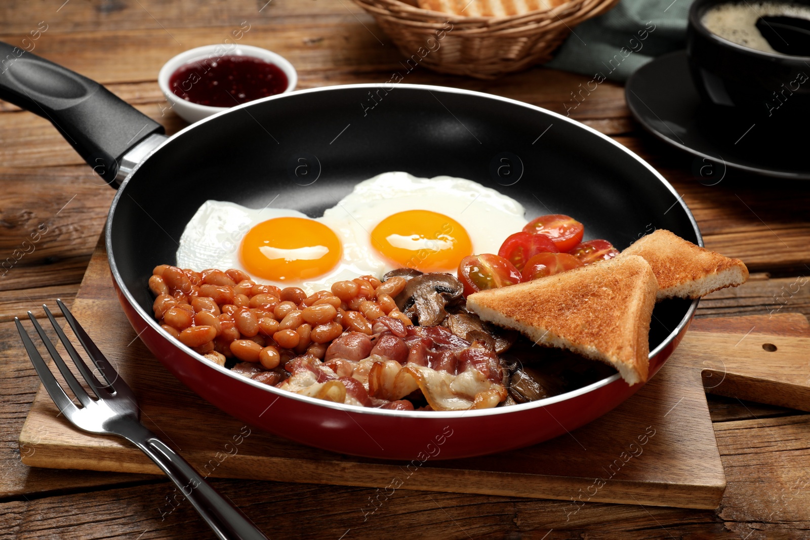 Photo of Frying pan with cooked traditional English breakfast on wooden table, closeup