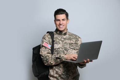 Cadet with backpack and laptop on light grey background. Military education