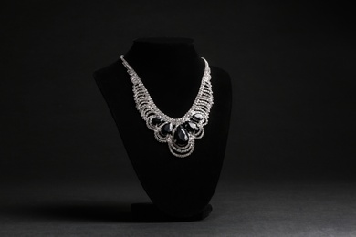 Elegant necklace on stand against black background. Luxury jewelry