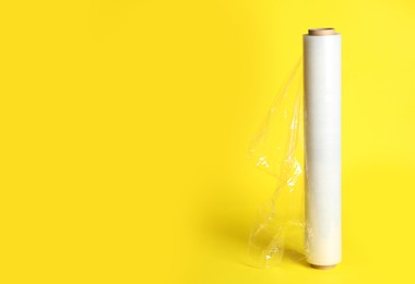 Photo of Roll of plastic stretch wrap film on yellow background, space for text