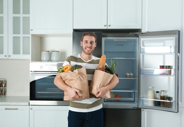 Photo of Man with fresh products near modern refrigerator in kitchen