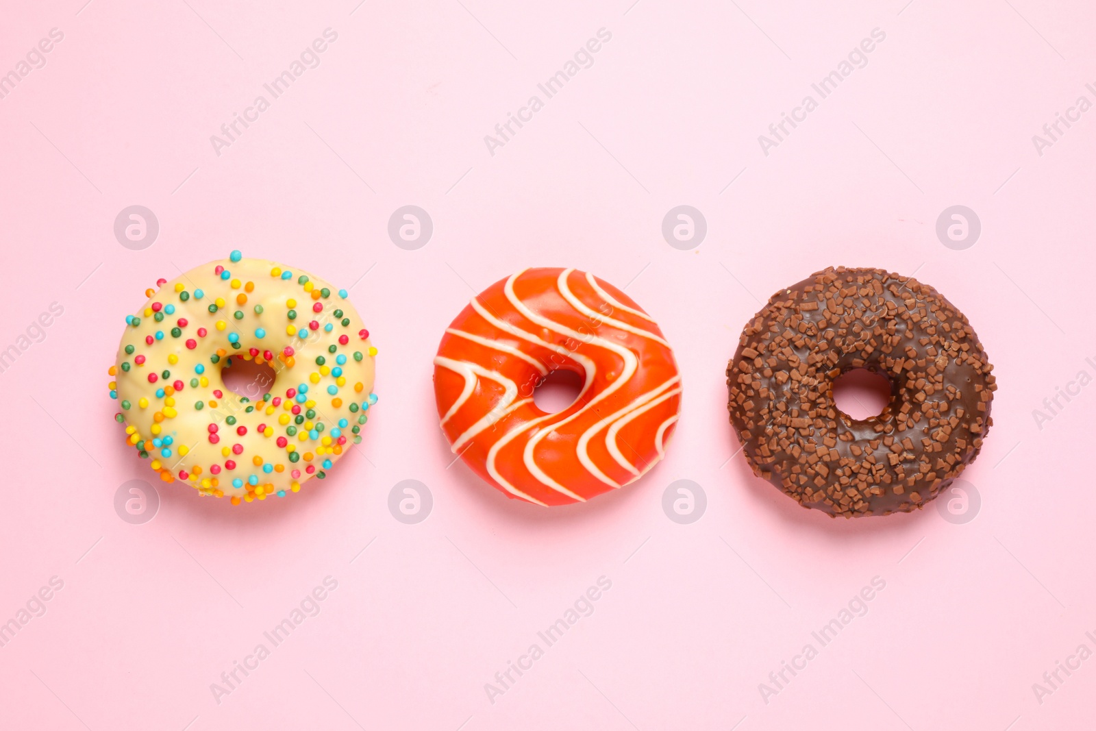 Photo of Delicious glazed donuts on pink background, flat lay