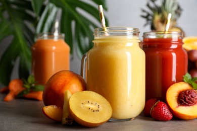 Photo of Delicious juices and fresh ingredients on grey table, closeup