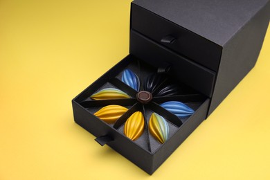Photo of Box of tasty chocolate candies on yellow background