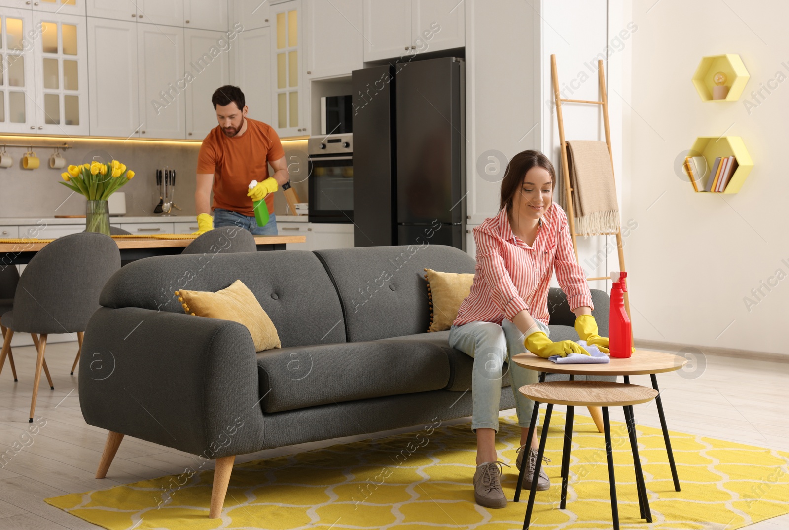 Photo of Spring cleaning. Lovely couple tidying up living room and kitchen together