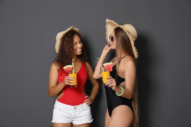 Photo of Beautiful young women in beachwear with cocktails on dark background