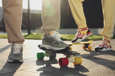 Photo of Woman and man with skateboards wearing stylish sneakers outdoors, closeup