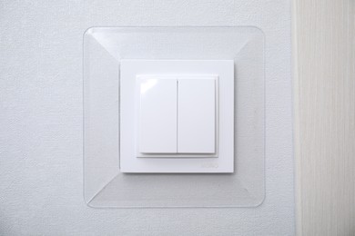 Photo of Modern plastic light switch on white wall, closeup