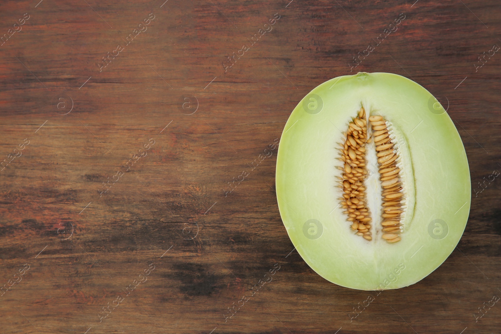 Photo of Half of tasty ripe melon on wooden table, top view. Space for text