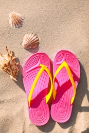 Photo of Stylish flip flops and sea shells on beach, flat lay