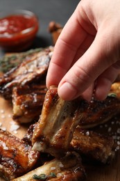 Photo of Woman with tasty grilled ribs at table, closeup