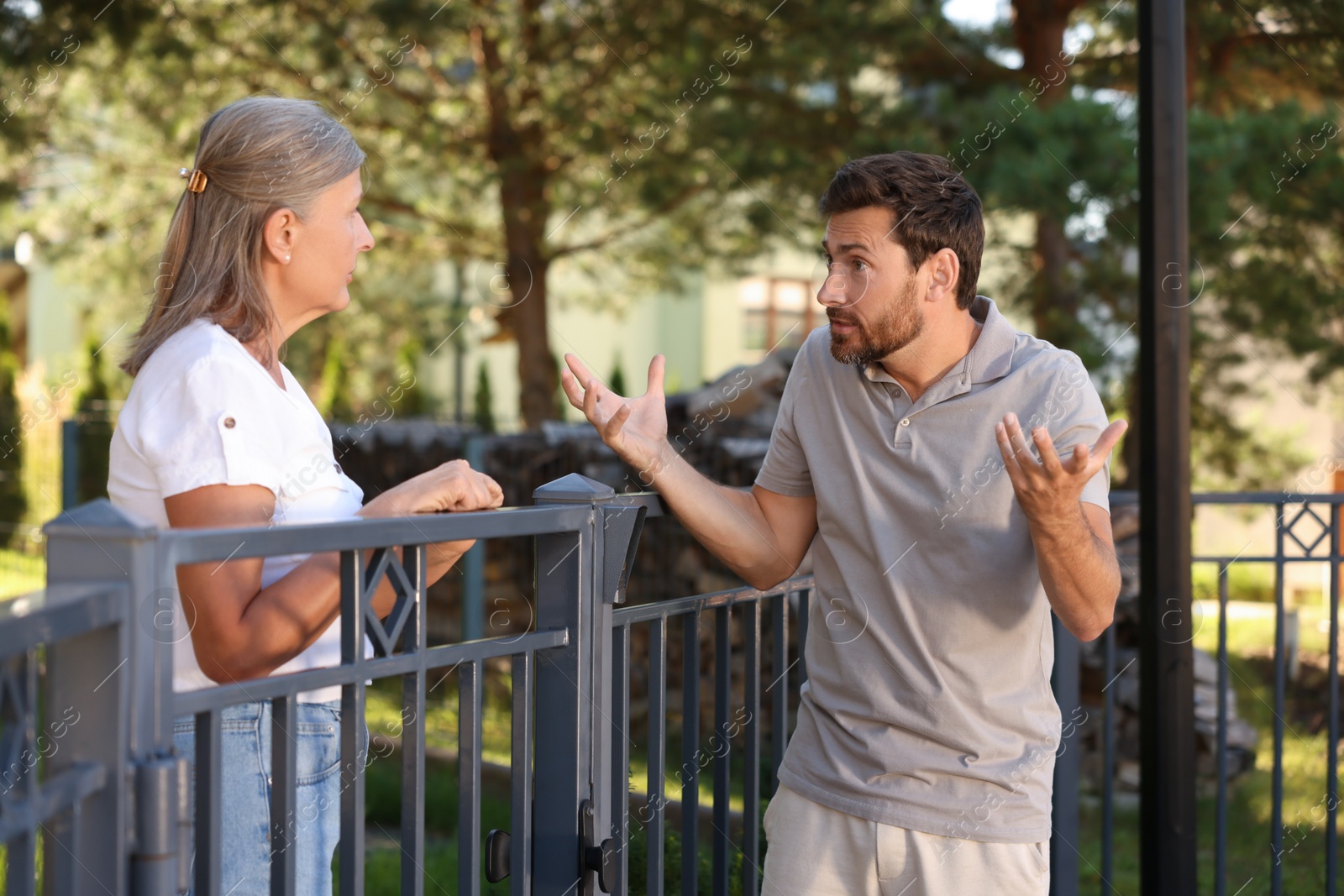 Photo of Emotional neighbours having argument near fence outdoors