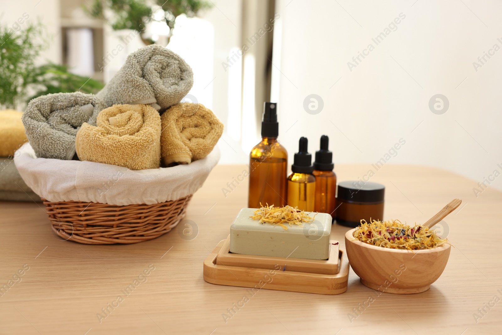 Photo of Soap bar, dry flowers, bottles of essential oils, jar with cream and towels on wooden table indoors. Spa time