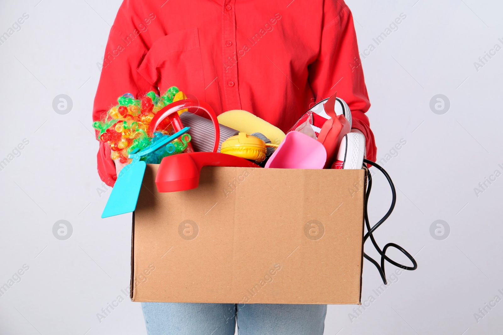 Photo of Woman holding box of unwanted stuff on white background, closeup