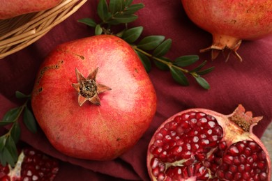 Photo of Fresh pomegranates and green leaves on table, top view