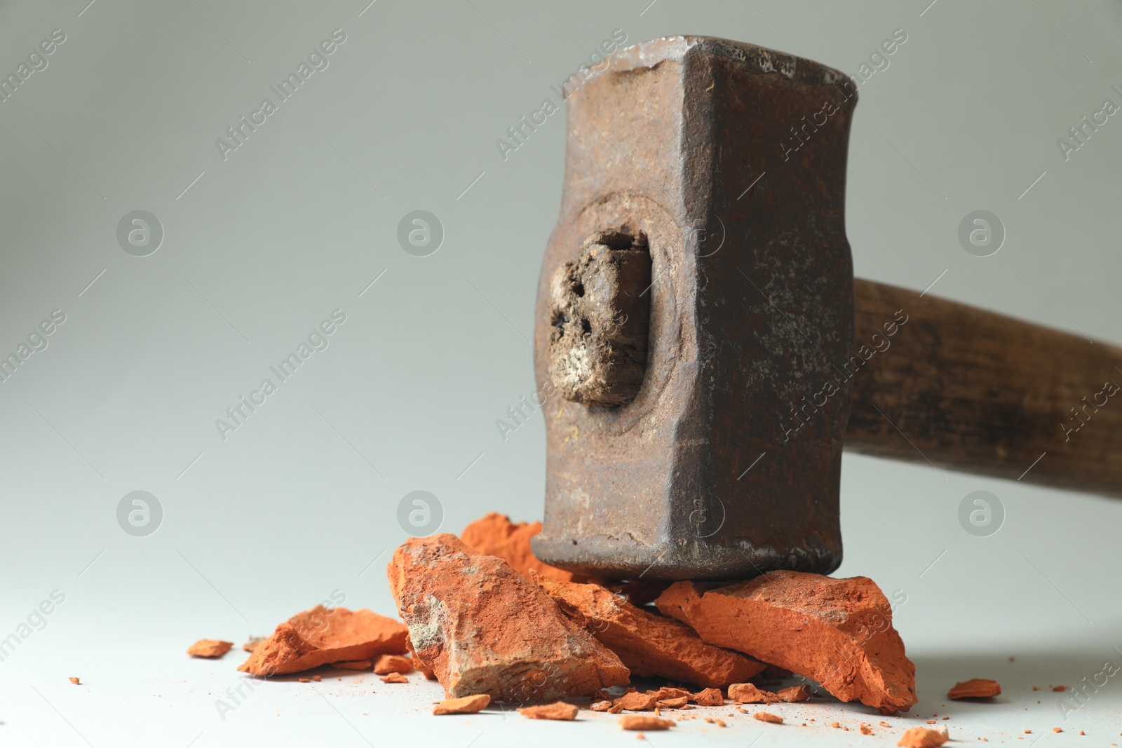 Photo of One sledgehammer and pieces of broken brick on grey background, closeup. Space for text