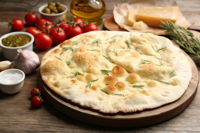 Photo of Focaccia bread with rosemary on wooden table, closeup