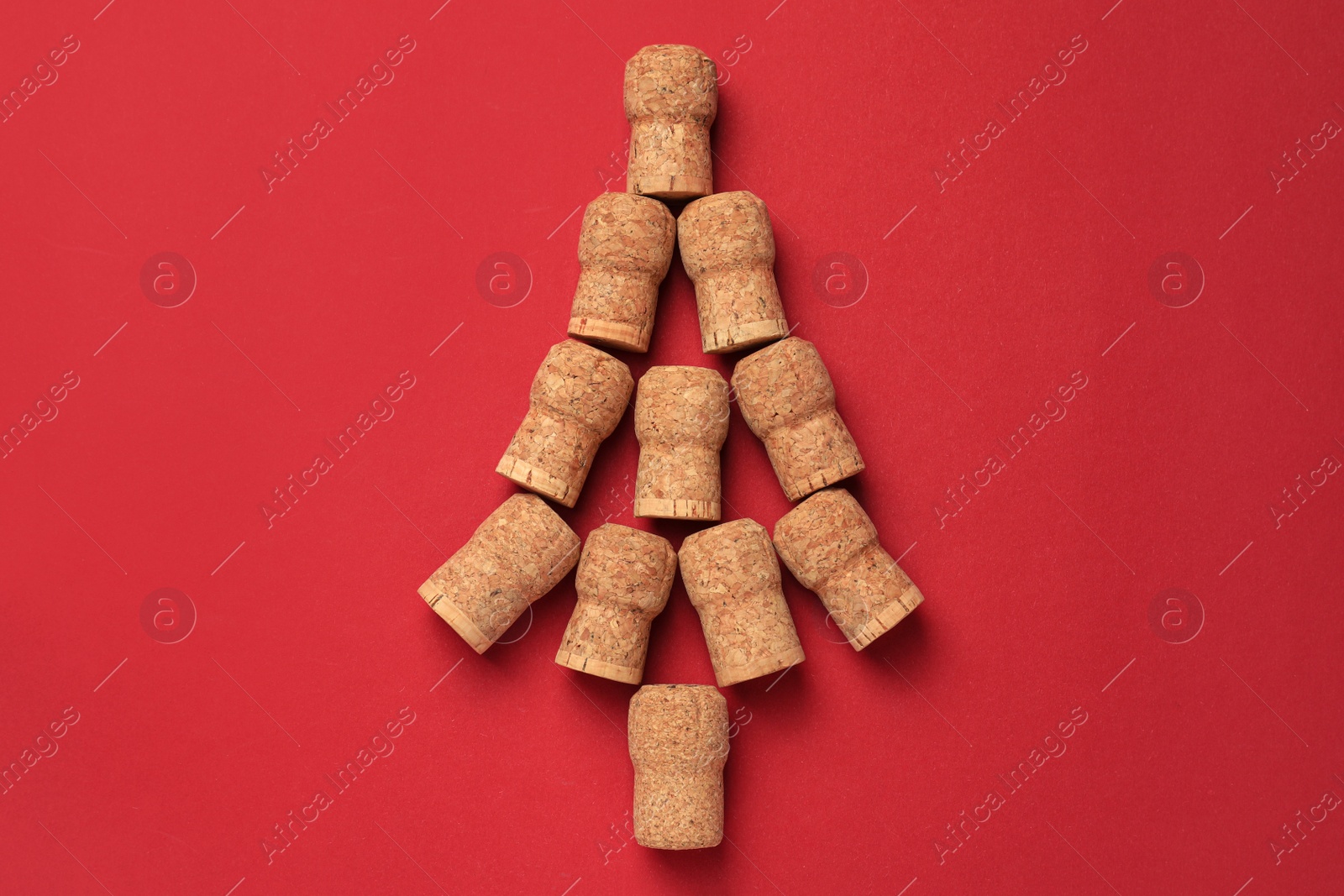 Photo of Christmas tree made of wine corks on red background, top view